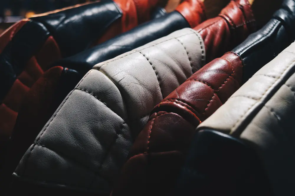 A close-up of a rack of quilted leather jackets in black, oxblood and cream, hanging at a market stall