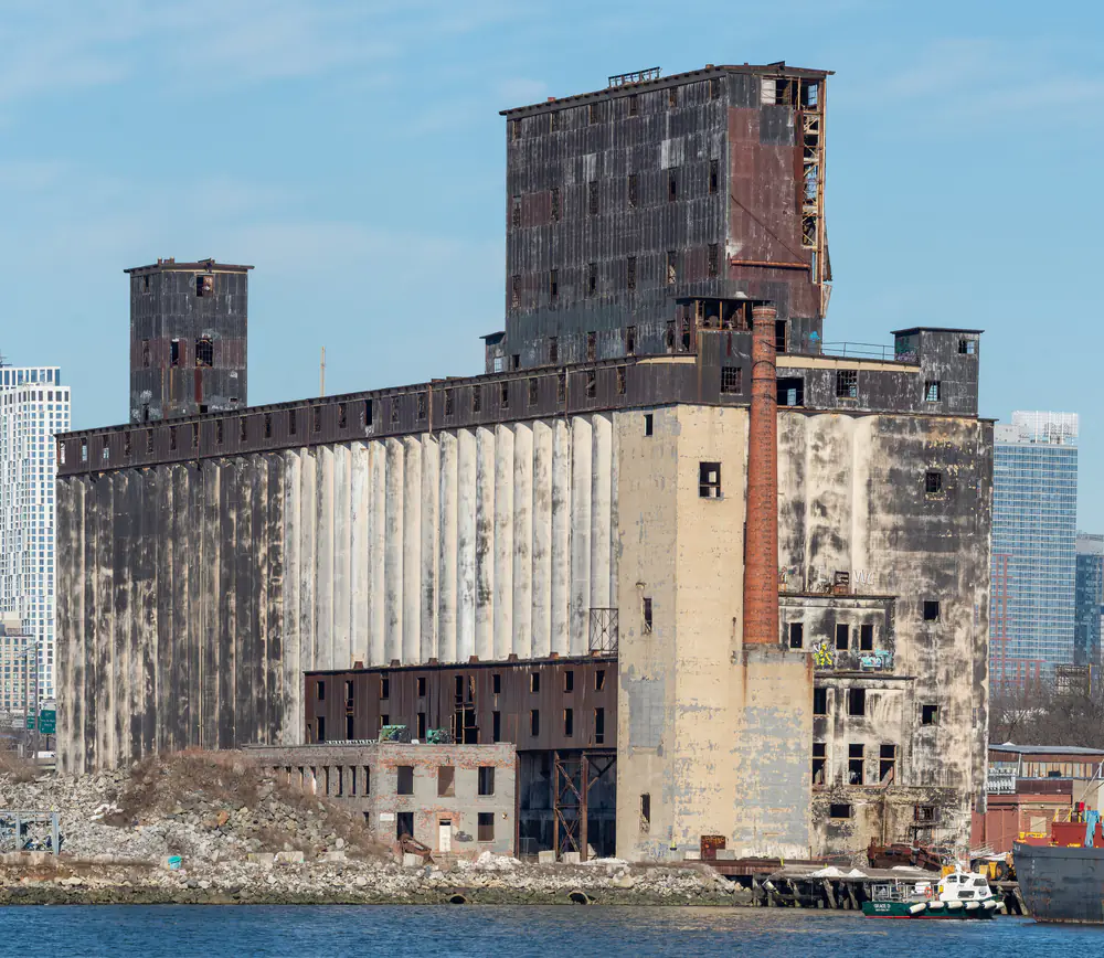 The Red Hook Grain Terminal: a row of tall weathered concrete silos standing empty against the sky, seen across the water