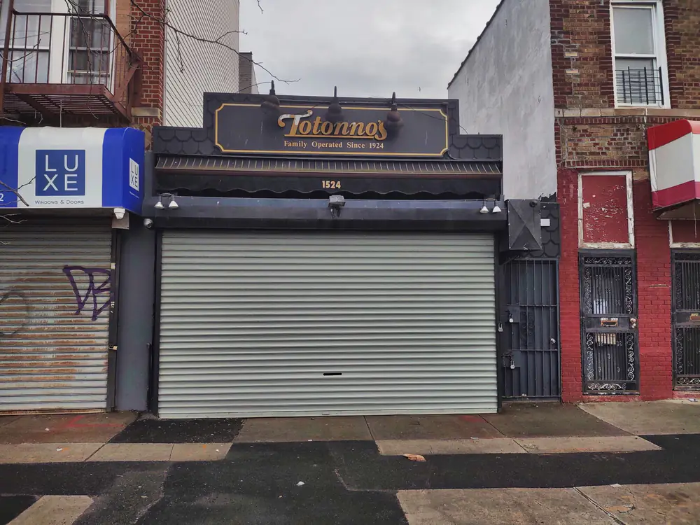 Totonno's shopfront on Neptune Avenue, Coney Island, shutter down beneath a sign reading Family Operated Since 1924